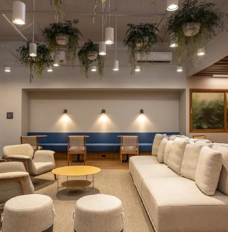 Profissional sorrindo durante videochamada exibida em notebook sobre a mesa.