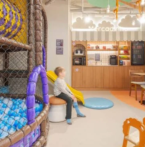 Profissional sorrindo durante videochamada exibida em notebook sobre a mesa.